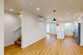 Located at 230 Tull Ct in Bellingham, WA, this contemporary three-bedroom, three-bathroom townhome is thoughtfully designed across three floors. The ground level features an attached garage with polished concrete floors, recessed lighting, and interior access — offering practical convenience from the moment you arrive. Carpeted staircases connect each level, providing a cohesive flow throughout the home. The main living floor is bright and open, seamlessly combining the kitchen, dining, and living areas. The kitchen is a standout, featuring white shaker cabinetry, stainless steel appliances, a central island with a undermount sink, and stylish pendant lighting overhead. Warm luxury vinyl plank flooring runs throughout this level, complemented by recessed lighting and a wall-mounted mini-split system. The upper floor hosts three well-proportioned bedrooms, each carpeted and filled with natural light through large windows fitted with blinds. Several rooms offer pleasant outdoor views of the surrounding greenery and neighborhood. Three full bathrooms serve the home, each finished with clean, modern fixtures including walk-in showers with matte black hardware. A balcony and ample closet storage across six closets round out the functional, well-appointed layout of this Bellingham townhome.