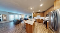 This well-appointed single-floor residence offers a thoughtfully designed open-concept layout that seamlessly connects the kitchen, dining, and living areas. The kitchen is a standout feature, showcasing warm wood-toned cabinetry extending to the ceiling, sleek white quartz countertops, a white subway tile backsplash, and a full suite of stainless steel appliances including a gas range, built-in microwave, dishwasher, and a french-door refrigerator. A central island with bar seating provides additional prep and dining space. Light wood-style flooring runs consistently throughout the entire residence, enhancing the sense of continuity and warmth. The open living area is bright and inviting, benefiting from abundant natural light streaming through large windows and a set of glass French doors that open to a private balcony. A dedicated dining area sits adjacent to the living space, defined by colorful wall art. The bedroom is a peaceful retreat with ample natural light from a large window, generous closet storage with double doors, and clean, neutral walls. Recessed lighting and modern fixtures contribute to the overall contemporary and refined ambiance of this well-designed residence.