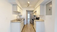 Located at 4555 Washington Rd in Atlanta, Georgia, this two-story residence offers a well-organized layout with thoughtfully updated finishes throughout. The main level features an open living area with light wood-style flooring, a ceiling fan, and vertical blinds that allow natural light to filter through. A carpeted staircase with a sleek metal railing connects the two floors seamlessly.

The galley-style kitchen is a standout feature, outfitted with white shaker cabinetry, granite countertops, a stainless steel refrigerator, electric range, and dishwasher. Light wood-style flooring and track lighting complete the clean, functional aesthetic.

The bedrooms are located on the upper level and are carpeted for comfort, each offering closet storage — including one room with a spacious walk-in closet equipped with wire shelving. A ceiling fan adds to the comfort of the primary bedroom.

Two full bathrooms serve the residence. One features a tub-shower combination with white tile surround, granite vanity countertop, and wood-style flooring. The second bathroom includes a glass-enclosed walk-in shower, a granite-topped vanity with gray cabinetry, and matching wood-style flooring. Both bathrooms are finished with brushed nickel hardware throughout.