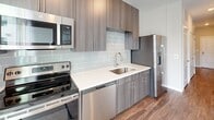 Located at 4301 Dominion Forest Cir in Glen Allen, Virginia, this thoughtfully designed one-bedroom, one-bathroom residence offers a clean, modern aesthetic across a single floor. Wood-style plank flooring flows consistently throughout the space, complementing the neutral gray wall palette and crisp white trim that define the interior's contemporary character.

The kitchen is a standout feature, showcasing flat-front cabinetry in a warm taupe finish, bright white quartz countertops, and a light gray subway tile backsplash. A full suite of stainless steel appliances — including a range, over-the-range microwave, dishwasher, and French door refrigerator — makes this kitchen as functional as it is stylish. The open sightlines connect the kitchen to the main living area, which features a sliding glass door that draws in natural light and provides access to an outdoor balcony.

The bedroom is a well-proportioned retreat with a ceiling fan with integrated lighting, neutral walls, and a closet accessible through a paneled white door. A connecting hallway leads to the full bathroom, which is finished with a dark wood-grain double vanity, white countertop, large mirror, and durable wood-style flooring. The layout is efficiently arranged, maximizing usability throughout. Overall, the space presents a clean, move-in-ready environment with modern finishes at every turn.