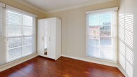 This single-floor studio in the Manor community of Los Angeles offers a thoughtfully designed layout that maximizes both function and style. The main living area is a standout, showcasing richly stained hardwood floors that reflect natural light streaming through large windows dressed with horizontal blinds. Crown molding lines the walls, adding a refined architectural touch, while an elegant arched doorway provides a graceful transition between spaces.

The kitchenette is efficiently arranged, featuring granite-patterned countertops, white cabinetry with sleek hardware, a stainless steel sink, a compact electric cooktop, and a small appliance unit below — providing essential cooking amenities in a compact footprint.

The bathroom offers a polished aesthetic with a marble-toned vanity countertop, a decorative vessel-style sink, a large mirror, and a glass-enclosed shower-tub combination accented by marble tile — creating a clean, spa-like atmosphere.

Storage is addressed through a freestanding white wardrobe with mirrored panels positioned within the living space. Multiple windows throughout offer views of the surrounding Los Angeles cityscape, filling the studio with abundant natural light and a vibrant urban connection.
