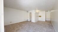 Located at 3253 Hillcrest Dr in San Antonio, TX, this one-bedroom, one-bathroom unit offers a practical and well-organized floor plan across a single level. The living area is carpeted and bathed in natural light, with vertical blinds framing a sliding door that opens to a private balcony overlooking a landscaped courtyard setting. The textured ceilings and crisp white walls create a clean, neutral backdrop throughout. The kitchen features tile flooring, white cabinetry, a built-in dishwasher, and a gas range, and flows naturally into a dedicated dining area. A pantry provides additional storage adjacent to the kitchen. The spacious primary bedroom offers generous proportions, plush carpeting, and a large window with vertical blinds that allow for natural light control. Two closets ensure ample storage throughout the unit. The full bathroom is fitted with a tub-shower combo, a vanity with a speckled countertop, and tile flooring. A utility room and hallway round out the functional layout. The balcony, accessible via a bold red entry door, extends the living space outdoors with views of the surrounding neighborhood and mature trees.