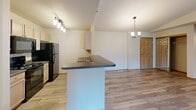 Located at 1125 S Ebenezer Ave in Sioux Falls, South Dakota, this single-floor unit offers a well-designed, open-concept layout that maximizes both space and functionality. The living area features vaulted ceilings, a ceiling fan, and plush carpet flooring, with a sliding glass door that opens to a private patio and lets in generous natural light. The kitchen is outfitted with light wood cabinetry, dark countertops, a central island with a built-in sink, black appliances, and stylish pendant lighting — all flowing seamlessly into the dining and living areas via durable hardwood-style flooring. Two full bathrooms serve the unit, each featuring light wood vanities, tub-shower combos, and hardwood-style floors. The bedrooms are generously sized, carpeted for comfort, and feature windows with outdoor views, providing a quiet, restful atmosphere. A dedicated laundry room includes in-unit washer and dryer hookups alongside wire shelving for added storage. Warm wood trim and neutral tones throughout create a cohesive, welcoming ambiance. The unit combines practical amenities with a comfortable, functional design well-suited for everyday living in Sioux Falls.