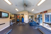 Located at 808 Gladstell St in Conroe, Texas, this single-floor fitness center is designed to support a full range of workout routines in a well-equipped, energizing environment. The space features striking vaulted ceilings that lend an open, airy feel, complemented by recessed and panel lighting throughout. Large windows and glass doors line the perimeter, flooding the interior with abundant natural light and offering views of the surrounding outdoor grounds.

The cardio zone is well-appointed with multiple treadmills, elliptical machines, and a stationary bike, all positioned to take advantage of the natural light and outdoor sightlines. A wall-mounted flat-screen TV adds to the motivational atmosphere. The strength training area includes a cable machine, adjustable weight benches, and a full rack of dumbbells, while a dedicated functional training section offers kettlebells, medicine balls in varying weights, and a storage unit for accessories.

Durable rubber flooring covers the workout areas, providing safety and comfort during exercise. Motivational signage is displayed throughout the space, adding character and energy. A ceiling fan and climate control ensure year-round comfort. The overall layout is thoughtfully organized to allow simultaneous use of cardio and strength equipment without congestion, making this fitness center a practical and well-rounded facility.