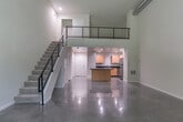 Located at 465 W San Carlos St in the heart of San Jose, CA, this two-story residence offers a thoughtfully designed layout spread across two floors. The main level, which comprises the majority of the living space, features gleaming polished concrete floors throughout, lending a contemporary industrial aesthetic to the open-plan living area. Large floor-to-ceiling windows flood the living room with natural light and frame serene views of the surrounding greenery, while a ceiling fan adds practical comfort.

The kitchen is well-equipped with light maple cabinetry, dark granite countertops, stainless steel appliances including a refrigerator, range, microwave, and dishwasher, and a central island that provides additional prep and storage space. Two full bathrooms serve the home — one on each level — with the upper bath featuring a tiled tub-shower combo, wood vanity, and large mirror.

The upper floor hosts the private bedroom, accessible via a sleek staircase with a modern cable-rail balustrade. A dedicated laundry area and multiple closets add to the home's functionality. The private balcony, framed by lush tree canopies, offers a peaceful outdoor retreat. In-unit laundry and ample storage round out this efficiently designed urban residence.