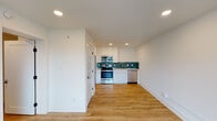 Located at 1500 Main St in Lynchburg, Virginia, this thoughtfully designed single-floor unit showcases a clean, contemporary aesthetic throughout. Warm hardwood-style flooring runs continuously across the living spaces, complementing the bright white walls and recessed lighting that keep the interior feeling open and airy.

The kitchen is a standout feature, outfitted with stainless steel appliances including an electric range, over-the-range microwave, dishwasher, and refrigerator. Sleek white cabinetry with gold-tone hardware frames the space, while a vibrant teal tile backsplash adds a bold pop of color. White quartz countertops and a stainless steel undermount sink with a gold faucet complete the polished look.

The bathroom is equally refined, featuring a walk-in shower adorned with large-format marble-look tile and a striking vertical accent strip of teal artisan tile. Gold-finished fixtures, including a handheld shower system, add an elevated touch, while a built-in niche provides functional storage.

A well-proportioned bedroom benefits from a large window that invites natural light and offers views of the surrounding area, along with a wall-mounted HVAC unit for climate control. An additional room provides flexible space for various uses. The overall layout is efficiently organized, delivering a modern and move-in-ready living environment.