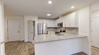 Located at 44 Courtlandt Street in New Brunswick, NJ, this well-appointed 2-bedroom, 2-bathroom residence offers a clean, modern aesthetic throughout its thoughtfully designed single-floor layout. The open-concept kitchen and living area serves as the heart of the home, featuring crisp white shaker cabinetry, granite countertops, a geometric tile backsplash, and a full suite of stainless steel appliances including a French-door refrigerator, over-the-range microwave, and dishwasher. A peninsula island provides additional counter space and an informal dining area. Light hardwood-style flooring flows seamlessly throughout the unit, complementing the bright, neutral color palette. Both bedrooms are well-proportioned, each offering ceiling fans with lighting, large windows that allow natural light and street views, and individual wall-unit HVAC systems. The primary bedroom is a comfortable, generously sized retreat. The two bathrooms are finished with large-format marble-style tile flooring and walls. One bathroom features a walk-in shower with full tile surround and built-in shelving, while the other includes a vanity with under-sink storage and a well-lit mirror. A dedicated entrance foyer and recessed lighting throughout complete this move-in-ready residence.