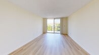 Located at 9060 NW 8th Street in Miami, FL, this one-bedroom, one-bathroom apartment offers a thoughtfully arranged single-floor layout with a comfortable sense of space throughout. The living room serves as the heart of the unit, featuring light wood-style flooring, cream-toned walls, and a textured ceiling that adds subtle character. A full-width sliding glass door floods the room with natural light and opens directly onto a private balcony, where a wrought iron railing frames lush, verdant views of the surrounding tree canopy and neighborhood rooftops beneath open Miami skies. The bedroom is generously proportioned, with the same light wood flooring, a wide window overlooking the greenery, and clean, neutral walls that offer a calm retreat. Two closets provide ample storage within the unit. The kitchen is outfitted with white cabinetry, a stainless steel sink, and white appliances including a range and refrigerator, all set atop classic light tile flooring beneath a grid-panel ceiling. The bathroom features a full soaking tub and shower combination, accented by warm beige tile work with a decorative mosaic border inlay. A hallway connects the rooms efficiently, completing a practical and well-lit floor plan ideal for comfortable everyday living.