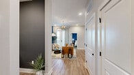 Located at 2220 Wilkinson Boulevard in Charlotte, NC, this thoughtfully designed two-bedroom, two-bathroom residence offers a functional and stylish single-floor layout. Light wood-look flooring flows throughout, complementing the clean white trim and modern finishes. The open-concept living, dining, and kitchen area serves as the heart of the home. The living room features a bold navy accent wall, a glass-globe chandelier, and direct access to a private balcony overlooking the surrounding community. The kitchen is outfitted with gray cabinetry, stainless steel appliances, a white subway tile backsplash, and a central island with seating beneath sleek pendant lighting. The primary bedroom offers generous proportions, a calming accent wall, large windows with natural light, and access to a walk-in closet. Its en-suite bathroom features large-format tile flooring and a glass-enclosed shower. The second bedroom is equally comfortable, with soft neutral tones and ample closet space. The second bathroom includes a soaking tub with marble-style tile surround and matte black fixtures. Additional spaces include a dedicated office, laundry room, and utility room, rounding out a complete and versatile floor plan.