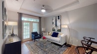 This thoughtfully designed single-floor residence offers a seamless blend of comfort and contemporary style. The open-concept living area is anchored by a tray ceiling, ceiling fan, and warm hardwood-style flooring, with large windows and a glass-paned door that fill the space with natural light and offer views of lush greenery outside. A tufted sofa, accent chair, and bold statement artwork contribute to the room's sophisticated character.

The kitchen is outfitted with rich espresso cabinetry, granite countertops, a breakfast bar peninsula, and a full suite of stainless steel appliances including a refrigerator, electric range, and microwave. An adjacent dining area features track lighting and hardwood-style flooring, providing an ideal setting for everyday meals or entertaining.

The bedroom is carpeted for comfort and features large windows with greenery views, a ceiling fan, and direct access to a walk-in closet. The bathroom is finished with granite countertops, warm wood cabinetry, a dual-sink vanity, and hardwood-style flooring.

A dedicated in-unit laundry room houses a full-size washer and dryer with built-in shelving for added storage. Throughout the residence, neutral gray walls, consistent finishes, and curated décor create a cohesive and welcoming ambiance.