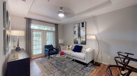 This thoughtfully designed single-floor residence offers a seamless blend of comfort and contemporary style. The open-concept living area is anchored by a tray ceiling, ceiling fan, and warm hardwood-style flooring, with large windows and a glass-paned door that fill the space with natural light and offer views of lush greenery outside. A tufted sofa, accent chair, and bold statement artwork contribute to the room's sophisticated character.

The kitchen is outfitted with rich espresso cabinetry, granite countertops, a breakfast bar peninsula, and a full suite of stainless steel appliances including a refrigerator, electric range, and microwave. An adjacent dining area features track lighting and hardwood-style flooring, providing an ideal setting for everyday meals or entertaining.

The bedroom is carpeted for comfort and features large windows with greenery views, a ceiling fan, and direct access to a walk-in closet. The bathroom is finished with granite countertops, warm wood cabinetry, a dual-sink vanity, and hardwood-style flooring.

A dedicated in-unit laundry room houses a full-size washer and dryer with built-in shelving for added storage. Throughout the residence, neutral gray walls, consistent finishes, and curated décor create a cohesive and welcoming ambiance.