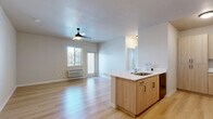 This single-floor, 2-bedroom, 2-bathroom unit offers a thoughtfully designed layout that maximizes functionality and comfort. The open-concept living and kitchen area serves as the heart of the space, featuring light wood-tone cabinetry with matte black hardware, white quartz countertops, a peninsula with an integrated sink, and a full suite of black appliances including a range, over-the-range microwave, and refrigerator. Abundant upper and lower cabinetry provides generous storage throughout the kitchen. The living area is bright and airy, with light streaming in through a large window and glass door that opens to an exterior view. A ceiling fan with a light fixture enhances comfort in the living space. Consistent light hardwood flooring flows throughout the entire unit, lending a clean and cohesive aesthetic. The primary bedroom is a well-proportioned retreat featuring a ceiling fan, a wall-mounted HVAC unit, and a window with natural light. The secondary bedroom is similarly bright, with a window and its own HVAC unit. Both bathrooms are finished with warm wood vanities, white quartz counters, and large mirrors. One bathroom features distinctive patterned tile flooring, adding a decorative touch. A closet provides additional storage, completing this efficiently arranged and modern unit.