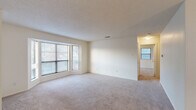 Located at 2401 Lakeview Rd in North Little Rock, AR, this well-appointed one-bedroom, one-bathroom residence offers a thoughtfully designed single-floor layout. The expansive living room is a standout feature, highlighted by large bay windows that fill the space with natural light and soft neutral carpeting that extends throughout the common areas. A pendant light anchors the adjoining dining area, which flows seamlessly into the galley-style kitchen. The kitchen is equipped with warm wood cabinetry, ample counter space, stainless steel appliances including a refrigerator and dishwasher, and durable hardwood-style flooring. The generously sized bedroom features a ceiling fan with light fixture, a window with natural light, and convenient access to multiple closets — four in total throughout the unit — providing exceptional storage. The bathroom is finished with a full soaking tub and tiled surround in a neutral stone-look pattern, lending a clean and polished aesthetic. Additional functional spaces include a dedicated laundry room, utility room, and a connecting hallway. A textured ceiling detail is present throughout, adding subtle architectural character to this comfortable and practical North Little Rock home.