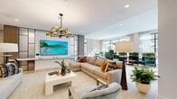 Located at 5905 Caravan Ct in Orlando, FL 32819, this expansive single-floor clubhouse and amenity lounge offers a generously proportioned open-plan layout designed for both relaxation and social engagement. Light-toned hardwood-style flooring runs throughout the space, complementing a crisp white palette accented by warm ambient cove lighting along the ceiling perimeter and recessed downlights overhead.

The main lounge area features a large sectional sofa with colorful accent pillows, a contemporary gold-and-bronze multi-arm chandelier, and a large-format wall-mounted display screen. Adjacent seating zones include a sunlit sitting area furnished with emerald green velvet armchairs positioned beside floor-to-ceiling windows and glass doors that open directly to an outdoor pool courtyard framed by palm trees and lush greenery.

A stylish wet bar with teal zellige tile cladding and white countertops serves as a central focal point, flanked by bar-height seating and pendant lighting. A billiards table anchors the game area nearby. A dramatic built-in shelving wall with curated décor and bold artwork provides a striking visual backdrop to a dedicated dining area with round tables and upholstered chairs. The space flows seamlessly between zones, creating a vibrant, resort-inspired communal environment.