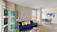 Located at 1550 Jackson Keller Rd in San Antonio, Texas, this single-floor model unit offers a well-appointed layout designed for comfortable living. The living room serves as the heart of the home, featuring warm neutral walls, plush carpeting, and a bright window that fills the space with natural light. A sliding glass door opens directly to a private outdoor patio, seamlessly connecting interior and exterior living areas with views of the surrounding greenery.

The kitchen is outfitted with dark espresso cabinetry, granite-style countertops, a full suite of black appliances, and tile flooring. A breakfast bar provides casual seating and transitions naturally into the adjacent dining area, which features a pendant light fixture and a sliding glass door offering additional outdoor access and natural light.

The bedrooms are carpeted and generously sized, each equipped with a ceiling fan and vertical blinds. The primary bedroom includes a mirrored sliding closet, while a second bedroom also benefits from direct patio access through a sliding glass door. The bathroom features tile flooring, a tub-shower combination with tiled surround, and dark vanity cabinetry consistent with the kitchen's design aesthetic. Throughout the unit, the warm beige palette and natural light create a cohesive and inviting ambiance.
