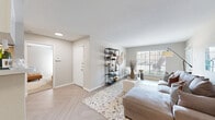 This single-story, 2-bedroom, 1-bathroom residence offers a well-organized layout across a comfortable footprint. The open-concept living room is a welcoming centerpiece, featuring light herringbone-patterned flooring, neutral walls, and multiple windows that fill the space with natural light. The galley-style kitchen is efficiently designed with white cabinetry, white countertops, a deep double sink with a modern faucet, subway tile backsplash, stainless steel appliances, and track lighting overhead. A half-wall with a curved archway connects the kitchen to the main living area, enhancing the open feel. The primary bedroom is a well-proportioned retreat with plush carpet, a ceiling fan, and a window providing natural light. The second bedroom features the same comfortable carpeting, a ceiling fan, and a distinctive full-wall chalkboard accent — a creative and versatile touch. The shared bathroom is clean and functional, featuring a single vanity with white cabinetry, a mirrored medicine cabinet, and a shower-tub combination. A hallway and closet round out the floor plan, ensuring practical storage. Throughout the residence, a cohesive neutral palette and consistent finishes create a bright, modern, and inviting atmosphere.