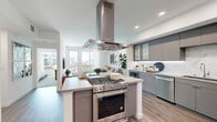 Located at 2457 Lomita Boulevard in Lomita, CA, this thoughtfully designed one-bedroom, one-bathroom residence offers a modern open-concept floor plan across a single level. The kitchen serves as a true centerpiece, featuring a large island with an integrated gas range, a dramatic stainless steel hood, sleek gray flat-front cabinetry, a marble-style backsplash, quartz countertops, and a full suite of stainless steel appliances including a dishwasher and refrigerator. The kitchen flows seamlessly into the living room, which is bathed in natural light from floor-to-ceiling windows and a glass door opening to a private balcony with exterior views. Wood-look flooring runs throughout the main living areas, adding warmth and continuity. The bedroom is a well-proportioned retreat featuring a ceiling fan, large windows that invite abundant natural light, and a dedicated closet. The full bathroom is elegantly appointed with a dual-entry glass walk-in shower, a soaking tub clad in large-format tile, a quartz-topped vanity with integrated sink, and wood-look flooring. Recessed lighting and a clean, neutral palette throughout lend the space a polished, contemporary feel.
