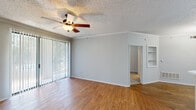 Located at 920 Meadow Creek Dr in Irving, Texas, this one-bedroom, one-bathroom residence offers a thoughtfully organized single-floor layout. The living area greets you with warm hardwood-style flooring, crown molding, a textured ceiling, and a ceiling fan. Large sliding glass doors with vertical blinds flood the room with natural light and provide outdoor views. Adjacent to the living area, the dining room features a stylish chandelier and a mirrored wall accent that enhances the sense of space. The kitchen is equipped with white cabinetry, stainless steel appliances including a gas range, microwave, and refrigerator, complemented by a peninsula counter that offers additional workspace and a natural flow into the dining area. The carpeted bedroom is a comfortable retreat with crown molding, a ceiling fan, and a window overlooking greenery. It connects directly to a generous walk-in closet outfitted with wire shelving on multiple levels for ample storage. The bathroom features white cabinetry and tiled shower walls with a bold accent tile detail. A dedicated utility room and an entrance with tile flooring complete this efficient and well-appointed home.