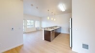Located at 333 NE 146th Ave in Portland, Oregon, this single-floor, 2-bedroom, 2-bathroom residence offers a thoughtfully designed layout with a clean, modern aesthetic throughout. The open-concept kitchen serves as a central hub, featuring dark espresso cabinetry, granite countertops, a peninsula with bar seating, stainless steel appliances — including a range, microwave, and refrigerator — and stylish pendant lighting that illuminates the space. Light wood-tone flooring extends through the kitchen and living area, creating a warm, cohesive feel. The living area receives natural light through large windows with views of the surrounding greenery. Both bedrooms are carpeted and well-sized, offering a comfortable, quiet retreat. The primary bedroom is notably spacious, featuring multiple windows that frame outdoor tree views, a built-in window bench with storage, and access to a dedicated walk-in closet. The en-suite primary bathroom is finished with granite countertops, dark wood cabinetry, a soaking tub, and light wood-tone flooring. The second bedroom includes a closet and large windows overlooking the neighborhood. The second bathroom mirrors the same quality finishes, complete with a tub/shower combo. The overall ambiance is bright, clean, and functional.