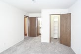 This single-floor residential unit offers a practical and comfortable layout designed for everyday living. The galley-style kitchen is efficiently arranged with warm oak cabinetry lining both sides, dark laminate countertops, a stainless steel sink, and white appliances including a refrigerator, dishwasher, and range. A skylight overhead brings natural light into the kitchen, enhancing the functional workspace. Hardwood-style flooring runs through the kitchen and bathroom areas, adding a clean, durable finish. The living area is generously sized and carpeted, featuring a ceiling fan with light fixture and a sliding glass door that opens to an outdoor space, accompanied by an additional window that allows natural light to fill the room. The layout flows smoothly from the living area into the rest of the unit. The bedrooms are carpeted and well-proportioned, with neutral walls and windows providing outdoor views and natural illumination. A standout feature of the primary bedroom is the dual closets — one with sliding doors and another standard closet — offering abundant storage. The bathroom is cleanly finished with hardwood-style flooring, a full tub-shower combination, a toilet, and a vanity with wood cabinetry. The overall ambiance is neutral, clean, and move-in ready.