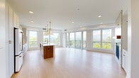 Located at 871 Sibley Memorial Hwy in Lilydale, MN, this thoughtfully designed 3-bedroom, 2-bathroom residence offers a refined modern aesthetic across a generous single-floor layout. The open-concept kitchen and living area serves as the heart of the home, featuring light hardwood flooring, recessed lighting, and an abundance of natural light. The kitchen is appointed with crisp white cabinetry, a large center island with a rich wood base and white quartz countertop, and gold pendant lighting that adds a warm, contemporary accent. Floor-to-ceiling windows and sliding glass doors open to a private balcony, framing sweeping panoramic views of the surrounding greenery and landscape. The living room includes a striking stone-surround fireplace flanked by built-in shelving and cabinetry, creating an elegant focal point. The three bedrooms are carpeted for comfort, with large windows providing ample natural light. The primary bathroom is spa-like, featuring a double vanity with walnut cabinetry, gold hardware, white quartz countertops, and backlit mirrors. A spacious walk-in closet with wire shelving provides generous storage. Clean white walls, black door hardware, and large-format tile flooring complete the polished, cohesive design throughout.