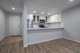 Situated in the vibrant Los Feliz neighborhood of Los Angeles, this single-floor residence at 1840 N Kenmore Ave offers a thoughtfully designed layout with clean, contemporary finishes throughout. Light wood-style flooring runs continuously across the living and kitchen areas, creating a cohesive and warm aesthetic.

The open-concept kitchen is a standout feature, outfitted with white shaker cabinetry, quartz countertops, and a classic white subway tile backsplash. Stainless steel appliances, including a range and built-in microwave, complement the modern design. A peninsula with a deep sink connects the kitchen to the living area, making it ideal for both cooking and entertaining.

The living area is generously proportioned and bathed in natural light, courtesy of large windows fitted with vertical blinds that offer both privacy and views of the surrounding greenery. Recessed lighting throughout the space adds a clean, polished look.

The bathroom is well-appointed with a full soaking tub and shower combination, a vanity with mirror, and neutral tiling that complements the overall palette of the home.

The entire unit maintains a bright, airy atmosphere with neutral gray and white tones, recessed lighting, and an efficient single-level floor plan that maximizes both comfort and functionality in this desirable Los Angeles location.