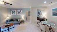 Located at 100 Northcreek Dr in Durham, NC, this single-floor residence offers a thoughtfully designed layout with a welcoming, cohesive aesthetic throughout. The living room serves as the heart of the home, featuring crown molding, a ceiling fan, a tiled fireplace, built-in shelving, and sliding glass doors that open onto a private balcony with outdoor seating and lush greenery views. Adjacent to the living area, the dining space provides an intimate setting with neutral tones and ample natural light. The kitchen is equipped with stainless steel appliances including a refrigerator, range, and over-the-range microwave, complemented by warm wood cabinetry, granite-style countertops, and hardwood flooring. The primary bedroom features soft carpet, a ceiling fan, a walk-in closet, and a large window that fills the room with natural light. Additional bedrooms are generously sized, each with ceiling fans, plush carpeting, and windows overlooking greenery. The bathrooms are well-appointed with granite-topped wood vanities, large framed mirrors, and hardwood floors; one includes a tub-shower combination with sliding glass doors. Throughout the residence, a consistent palette of neutral tones and tasteful accents creates a comfortable, inviting atmosphere.
