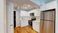 Located at 5959 Broadway in the Riverdale neighborhood of the Bronx, unit 414 is a thoughtfully renovated residence that combines modern finishes with functional design across a single floor. The open-concept living and dining area is anchored by warm hardwood flooring that extends throughout the space, recessed lighting overhead, and soft neutral-toned walls that create a clean, airy atmosphere. Natural light filters in through large windows, each equipped with a radiator beneath for year-round comfort.

The kitchen is a standout feature, outfitted with crisp white shaker-style cabinetry, white subway tile backsplash, light countertops, and a full suite of stainless steel GE appliances including a refrigerator, electric range, and over-the-range microwave. The kitchen opens directly to the living area, making the layout ideal for everyday living and entertaining.

The bedrooms continue the hardwood flooring and neutral palette, offering well-proportioned spaces with natural light and easy access to the rest of the unit. The bathroom is finished with floor-to-ceiling white subway tile surrounding a soaking tub and shower combination enclosed by a sleek sliding glass door with brushed nickel hardware, delivering a polished, contemporary look throughout.