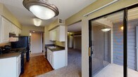 Located at 8125 Summerset Dr in Colorado Springs, Colorado, this single-floor residence offers a practical and functional layout spread across several interconnected living areas. The galley-style kitchen is a standout feature, equipped with white cabinetry, dark granite-style countertops, a double stainless steel sink, and black appliances including a range and refrigerator. Warm hardwood-style flooring runs throughout the kitchen, providing a clean contrast to the cabinetry. A secondary sink area near the entry offers added utility.

The living room is generously proportioned, featuring plush carpeting, a textured ceiling, a built-in corner fireplace with a surrounding shelf, and a sliding glass door that opens to an outdoor area, allowing natural light to fill the space. The bedroom areas are carpeted and bright, with multiple windows dressed in vertical blinds that diffuse natural light effectively.

The bathroom includes a full tub and shower combination with tiled surround and hardwood-style flooring. A dedicated utility room houses the washer, water heater, and furnace, consolidating mechanical systems efficiently. Overall, the space maintains a neutral, understated palette throughout.