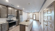 Located at 1445 S Egret Bay Blvd in League City, Texas, this one-bedroom, one-bathroom residence offers a thoughtfully designed single-floor layout with modern finishes throughout. Wood-look flooring runs consistently across all rooms, lending a clean and cohesive aesthetic to the entire space.

The kitchen serves as a central highlight, featuring rich dark-toned cabinetry, granite countertops, a center island with a built-in sink, and a full suite of stainless steel appliances including a refrigerator, electric range, and built-in microwave. Pendant lighting above the island adds a stylish touch, while recessed ceiling lights provide ample illumination.

The bedroom is a comfortable retreat, fitted with a ceiling fan and a window that brings in natural light and outdoor views. Five-panel interior doors are found throughout, contributing to the home's contemporary character.

The bathroom is generously sized, boasting a dual-sink vanity with granite countertops, dark cabinetry with brushed hardware, and a large framed mirror. An adjacent walk-in closet offers built-in wire shelving on multiple walls, maximizing storage capacity.

A private outdoor area overlooks the surrounding landscape, completing this well-equipped and move-in-ready residence.