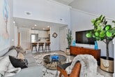 This two-story residence in Atlanta's 30312 area offers a well-designed layout spread across two distinct levels. The main floor centers around an open-concept living and kitchen space, where light hardwood flooring runs throughout and connects the areas seamlessly. The kitchen is outfitted with white cabinetry reaching toward the ceiling, stainless steel appliances including a refrigerator, range, and microwave, and a granite-topped island with bar seating — a practical and stylish hub for cooking and entertaining. The adjacent living area features generous wall height, allowing for prominent artwork display and a bright, airy atmosphere, with access to a balcony that brings in natural light.

Two carpeted bedrooms on the main level are well-proportioned, each with windows dressed in layered blinds and curtains. Two bathrooms mirror each other in design, featuring white vanity cabinetry with granite countertops, large mirrors, and light hardwood flooring.

The upper level opens to a flexible loft-style space with carpet, a window for natural light, and an open railing overlooking the lower floor — ideal for use as a reading nook, office, or lounge area. A bookcase and accent seating complete this versatile retreat.