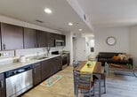 Located at 6350 Griffin Rd in Davie, Florida, this single-floor residence offers a well-designed, open-concept layout that seamlessly connects the kitchen, dining, and living areas. The entryway greets visitors with a bold teal door, wood-look flooring, and a convenient wall-mounted key rack, setting a clean, modern tone throughout.

The kitchen is outfitted with rich dark espresso cabinetry, granite-style countertops, and a full suite of stainless steel appliances including a refrigerator, range, microwave, and dishwasher. The open layout flows directly into the dining area and living room, which features wood-look flooring, a ceiling fan, and a window offering views of the surrounding community.

The bedrooms are comfortably proportioned, each featuring wood-look flooring, ceiling fans, and closet storage. The bathrooms are finished with granite vanity countertops and dark cabinetry, with one bathroom featuring a full tub-shower combination with white tile surround and the other functioning as a half bath with a large vanity mirror. Recessed lighting and neutral white walls throughout contribute to a bright, airy atmosphere that is both functional and inviting.