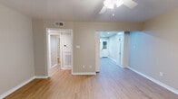 This single-story, 2-bedroom, 1-bathroom unit is thoughtfully laid out to maximize functionality across its compact footprint. Warm-toned, light wood-style flooring runs consistently throughout every room, creating a cohesive and clean aesthetic. Neutral beige walls and white trim provide a bright, understated backdrop across the entire unit.

The living room serves as the primary gathering space, featuring a ceiling fan with light fixture and a window fitted with horizontal blinds that admit natural light. A front entry door opens directly into this area, offering a welcoming first impression.

The kitchen is well-appointed with white shaker-style cabinetry, light countertops, recessed lighting, and a full suite of stainless steel appliances including a dishwasher, range, and refrigerator. A secondary door in the kitchen provides additional access to the exterior.

Both bedrooms are comfortably proportioned, each equipped with a ceiling fan and closet storage. The primary bedroom features a large double sliding closet with paneled doors, while the secondary bedroom includes a single closet. Windows with blinds in each bedroom bring in natural light and outdoor views. A hallway connects the bedrooms and shared spaces, maintaining an efficient and practical flow throughout the unit.