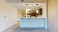 Located at 340 Dixwell Ave in New Haven, CT, this one-bedroom, one-bathroom unit offers a thoughtfully designed layout across a single floor. The open-concept living, dining, and kitchen area serves as the heart of the home, anchored by a peninsula with a granite countertop that provides both workspace and a natural divide between the kitchen and living space. Pendant lighting hangs above the peninsula, adding a modern touch. The kitchen is well-appointed with dark espresso shaker-style cabinetry, stainless steel appliances including a refrigerator, range, and microwave, and light granite countertops throughout. Light gray wood-style flooring runs through the main living area, creating a clean and cohesive aesthetic. The bedroom is a standout feature, distinguished by warm natural wood-paneled walls and a matching wood-paneled ceiling that lend a rustic, cabin-inspired character. Large windows in the bedroom allow ample natural light and provide views of the surrounding greenery. Two closets offer convenient storage throughout the unit. The bathroom is clean and functional, featuring light wood-style flooring, a dark vanity, and accessible design elements including a grab bar. The unit's combination of modern finishes and warm natural materials creates a balanced and inviting living environment.