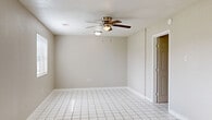 Located at Thomas Manor in Crosby, TX, this single-story home offers a practical and functional layout across three bedrooms, one bathroom, a kitchen, and a dining room. White tile flooring runs consistently throughout the home, creating a cohesive and easy-to-maintain interior. The living and dining areas are bright and open, benefiting from multiple windows with blinds that allow natural light to filter in, along with ceiling fans to promote airflow and comfort. The spacious primary bedroom features its own ceiling fan and ample room for furnishings. Additional bedrooms are well-proportioned with tile flooring and ceiling fans, with windows providing views of the surrounding area. The kitchen is equipped with warm oak cabinetry, tile countertops, a diagonal tile backsplash, a double-basin sink, a dishwasher, and an electric range with overhead ventilation — all set on matching tile flooring. A dedicated pantry with built-in shelving is conveniently accessible from the kitchen. The bathroom includes a soaking tub, vanity with storage, and a privacy window for natural light. Textured ceilings are found throughout, and neutral wall tones give the home a clean, move-in ready appearance.