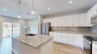 Located at 6 Crossgates Mall Rd in Albany, NY, this well-appointed 1-bedroom, 2-bathroom residence offers a thoughtfully designed single-floor layout with modern finishes throughout. The open-concept kitchen serves as the heart of the home, showcasing a large center island with a granite countertop, undermount sink, and pendant lighting. White shaker cabinetry, a subway tile backsplash, and a full suite of stainless steel appliances — including a French door refrigerator, range, microwave, and dishwasher — complete the space. Light-toned hardwood flooring flows seamlessly through the kitchen, living areas, and bedroom, creating a cohesive and airy feel. The spacious bedroom features a ceiling fan, a wide window with outdoor views of the surrounding neighborhood, and access to two generously sized walk-in closets outfitted with wire shelving systems for ample storage. The primary bathroom offers a glass-enclosed walk-in shower, a white vanity with granite countertop, a large mirror, and tile flooring. A second full bathroom includes a soaking tub with shower, a matching vanity, and tile flooring. Neutral warm-gray wall tones and recessed lighting throughout lend the space a clean, contemporary ambiance.
