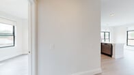 Located at 118 Park Ave in Rutherford, NJ, this thoughtfully designed single-floor residence showcases a clean, modern aesthetic with consistent light wood flooring and crisp white walls throughout. The open-concept kitchen is a standout feature, equipped with sleek, high-gloss gray cabinetry, stainless steel appliances including a gas range, built-in microwave, and dishwasher, paired with a white quartz peninsula countertop. Recessed lighting and large black-framed windows flood the living and kitchen areas with natural light while offering views of the surrounding Rutherford neighborhood. The spacious living area benefits from multiple windows on two walls, creating a bright, airy atmosphere. The bedrooms are generously sized, with large black-framed windows providing neighborhood views, and one bedroom features dual sets of double closets offering ample storage. The bathroom is finished with modern wood-toned cabinetry, a white quartz vanity top, an oversized mirror, and sleek marble-style tile flooring. Clean white millwork, including detailed door casings and crisp baseboards, adds a polished finishing touch throughout the entire space.