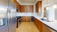 Located in San Diego's 92101 zip code, this well-designed one-bedroom, one-bathroom residence offers a thoughtfully arranged single-level floor plan with a bright, neutral palette throughout. Light wood-style flooring extends across the main living areas, complementing the clean, modern aesthetic.

The kitchen is a standout feature, equipped with warm walnut-toned cabinetry, white quartz countertops, stainless steel appliances including a gas range, refrigerator, and built-in microwave, a subway tile backsplash, a stainless steel sink, and a built-in wine cooler. A breakfast bar with pendant lighting connects the kitchen to the living area, which benefits from large windows and a ceiling fan, flooding the space with natural light. A balcony door provides outdoor access and urban views.

The bedroom is carpeted for comfort, featuring sliding windows, direct balcony access, and a door leading to a dedicated walk-in closet outfitted with multiple hanging rods and shelving. The bathroom includes a full soaking tub with tiled surround, dark tile flooring, a wood-framed mirror, and a vanity with ample storage. The overall ambiance is clean, contemporary, and well-lit.