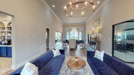 Located at 14723 W Oaks Plaza Dr in Houston, TX, this single-story leasing office presents a refined and welcoming environment designed to impress. The main lounge area commands attention with soaring ceilings adorned with bold crown molding and a striking circular chandelier. Rich herringbone-patterned hardwood flooring runs throughout, anchoring the space with warmth and elegance. Deep navy blue velvet sofas and neutral accent chairs are thoughtfully arranged to create distinct yet open seating areas, complemented by live-edge wood coffee tables and curated abstract artwork.

A glass-walled room provides a semi-private conference or meeting space that maintains visual connectivity to the main floor, while a cozy secondary lounge offers a flat-screen TV, tufted chairs, and a large arched window that floods the room with natural light. The dedicated office area features a curved executive desk positioned beneath a dramatic arched window bay, offering panoramic views of the community pool and surrounding landscape. Geometric patterned drapery adds a decorative touch throughout. The overall ambiance is polished and contemporary, balancing professional functionality with inviting, hospitality-inspired design.