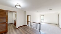 This 4-bedroom single-floor residence offers a practical and well-designed layout with a mix of hardwood flooring and plush carpeting throughout. The open living area is anchored by a distinctive raised entryway platform with rich hardwood flooring, wrought iron stair railing, and louvered closet doors — adding a subtle architectural character to the space. Flush-mount ceiling fixtures provide consistent overhead lighting, while white walls and clean baseboards with warm wood trim create a bright, neutral backdrop throughout.

The bedrooms are generously proportioned, with the primary bedroom standing out as a particularly spacious retreat. Each bedroom features soft wall-to-wall carpeting, large sliding glass doors or windows that invite ample natural light and outdoor views of surrounding greenery, and baseboard heating for year-round comfort. Several bedrooms include wide bi-fold closets, offering substantial built-in storage. The kitchen is positioned near the main entryway and features dark wood cabinetry. A central hallway connects the bedrooms, providing a logical and efficient flow through the home. Overall, the space presents a clean, functional, and comfortable living environment with practical design choices throughout.