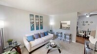 Located at 404 Jones Ferry Rd in Carrboro, NC, this two-bedroom, one-bathroom single-floor residence offers a practical and well-appointed layout. The combined kitchen and living area forms the heart of the home, where a galley-style kitchen showcases white cabinetry, dark granite-style countertops, stainless steel appliances including a refrigerator, electric range, dishwasher, and over-the-range microwave, and wood-style flooring. A pass-through opening connects the kitchen to the living area, enhancing the open feel. The living room features plush carpeting, a front-facing window that brings in natural light, and a textured ceiling. Both bedrooms are carpeted and offer natural light through windows; the primary bedroom includes a walk-in closet, while the second bedroom provides ample space and additional storage. The full bathroom is outfitted with a tub-shower combination and clean white fixtures. A dedicated in-unit laundry closet with a stacked washer and dryer adds everyday convenience. A ceiling fan in the kitchen/dining area and consistent neutral tones throughout contribute to the cohesive and functional character of this Carrboro residence.