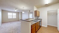Located at 1750 Village Commons Dr in Conway, Arkansas, this well-appointed 2-bedroom, 3-bathroom single-floor residence offers a functional and comfortable layout. The open-concept kitchen flows seamlessly into the combined dining and living area, creating a connected space ideal for everyday living and entertaining. The kitchen features warm honey-toned cabinetry, granite-style countertops, a double-basin sink, a dishwasher, and black appliances including a range and built-in microwave, all set atop durable wood-look flooring. A pendant light and ceiling fan illuminate the transition into the carpeted living area, which receives natural light through a large window. Both bedrooms are carpeted and bright, with natural light provided by multiple windows fitted with blinds. The spacious primary bedroom includes its own ceiling fan. Each bedroom is complemented by adjacent bathrooms featuring rich wood vanities with granite-style countertops, large mirrors, and wood-look flooring. Four closets throughout the unit provide generous storage. A dedicated laundry room adds everyday convenience. The overall ambiance is clean, neutral, and move-in ready.