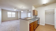 Located at 1750 Village Commons Dr in Conway, Arkansas, this well-appointed 2-bedroom, 3-bathroom single-floor residence offers a functional and comfortable layout. The open-concept kitchen flows seamlessly into the combined dining and living area, creating a connected space ideal for everyday living and entertaining. The kitchen features warm honey-toned cabinetry, granite-style countertops, a double-basin sink, a dishwasher, and black appliances including a range and built-in microwave, all set atop durable wood-look flooring. A pendant light and ceiling fan illuminate the transition into the carpeted living area, which receives natural light through a large window. Both bedrooms are carpeted and bright, with natural light provided by multiple windows fitted with blinds. The spacious primary bedroom includes its own ceiling fan. Each bedroom is complemented by adjacent bathrooms featuring rich wood vanities with granite-style countertops, large mirrors, and wood-look flooring. Four closets throughout the unit provide generous storage. A dedicated laundry room adds everyday convenience. The overall ambiance is clean, neutral, and move-in ready.