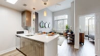 Located at 1 Shearwood Place in New Rochelle, NY, this thoughtfully designed one-bedroom, one-bathroom residence offers a modern, open-concept layout with stylish finishes throughout. The combined kitchen and living area serves as the heart of the home, featuring elevated ceilings with a ceiling fan and large floor-to-ceiling windows that flood the space with natural light and offer views of the outdoors. The kitchen is equipped with wood-toned cabinetry, a crisp white quartz waterfall island with seating, pendant lighting, stainless steel appliances including a French door refrigerator and dishwasher, and a subway tile backsplash. Light hardwood flooring flows seamlessly throughout. The living area is generously proportioned, providing ample room for comfortable seating arrangements. The bedroom offers a serene retreat with natural light from a large window, neutral tones, and wood-look flooring. The bathroom features a wood-grain vanity with a white countertop, a framed mirror, tile flooring, and a shower-tub combination. Clean lines and contemporary design choices unify every room, creating a cohesive and inviting living environment.