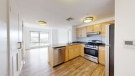 Located at 695 Atlantic St in Stamford, Connecticut, this two-bedroom, two-bathroom residence offers a well-organized single-floor layout designed for comfortable urban living. The open-concept kitchen is a standout feature, equipped with light maple cabinetry, a peninsula with a built-in sink and dishwasher, stainless steel gas range and refrigerator, and a subway tile backsplash — all set atop warm hardwood-style flooring that extends into the living area. Large windows in the living space frame elevated views of the Stamford cityscape, filling the area with natural light. The primary bedroom continues the hardwood-style flooring and features a generous picture window with expansive city views. The second bedroom is finished with plush carpet and dual windows that also offer elevated neighborhood vistas. Both bathrooms are finished consistently with white cabinetry, warm-toned countertops, tiled tub-shower combinations, and mosaic tile flooring. The residence includes an impressive six closets throughout, providing exceptional storage — including a carpeted walk-in closet with wire shelving. A connecting hallway ties the layout together efficiently, creating a clean, functional flow throughout the home.