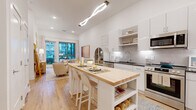 Located at 3615 Tryclan Drive in Charlotte, NC, this thoughtfully designed one-bedroom, one-bathroom residence offers a bright and modern living experience across a single floor. The open-concept layout connects the kitchen and living room seamlessly, creating an inviting and functional space.

The kitchen is a standout feature, boasting high-gloss white cabinetry that extends to the ceiling, dark granite countertops, a tiled backsplash, and a full suite of stainless steel appliances including a refrigerator, range, microwave, and dishwasher. A freestanding island with a butcher block top and built-in wine rack provides additional prep space and casual seating.

The living room is bathed in natural light from floor-to-ceiling glass doors that open to an outdoor area, offering views of the surrounding community. The space features warm light wood flooring that flows throughout the entire residence.

The bedroom is a serene retreat, offering generous proportions, large windows with outdoor views, and warm natural light. The bathroom features an elongated vanity with dark granite countertops, white cabinetry, a glass-enclosed shower, and direct access to a dedicated closet.

Clean white walls, recessed lighting, and cohesive finishes give this residence a polished, contemporary ambiance.