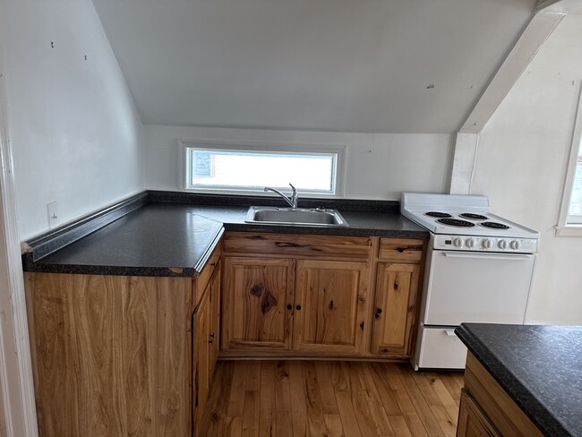 View into the kitchen from the dining area. Bathroom to the left, entry to the right. - 25 Monroe St