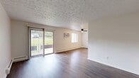 Located at 1876 Sunset Ave in Cincinnati, Ohio, this one-bedroom, one-bathroom unit offers a practical and well-appointed single-floor layout. Rich, dark hardwood-style flooring runs consistently throughout the space, complementing the neutral white and beige walls that create a bright, clean aesthetic.

The living room is generously proportioned, offering ample room for flexible furniture arrangements. A sliding glass door floods the area with natural light and provides direct outdoor access with views of greenery. A ceiling fan and wall-mounted AC unit add functional comfort, while baseboard heating ensures year-round climate control. A textured ceiling adds subtle character throughout the common areas.

The bedroom is a comfortable, well-sized retreat featuring a large window that allows natural light and outdoor views. Two separate arched-panel closet doors provide excellent storage options, and the same warm hardwood-style flooring continues seamlessly from the rest of the unit.

The bathroom is finished in a clean, all-white palette with square subway tile surrounding a full bathtub and shower combination. The warm wood-tone flooring contrasts neatly with the white fixtures and cabinetry, lending a modern yet timeless feel. Overall, this unit delivers a cohesive, move-in ready living experience in a straightforward and functional design.