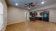 This single-story unit on Covington Way in Conway, Arkansas, offers a thoughtfully designed layout that balances open communal spaces with comfortable private areas. The living and dining area is expansive and open, featuring warm-toned hardwood-style flooring, recessed lighting, and a ceiling fan that enhance both functionality and visual appeal. The space flows seamlessly into the kitchen, which is outfitted with rich dark-stained wood cabinetry, granite-style countertops, a breakfast bar peninsula, and a full suite of black appliances including a refrigerator, range, microwave, dishwasher, and sink. The hardwood-style flooring continues throughout the main living areas, lending a cohesive aesthetic.

The bedrooms are carpeted for comfort and each include ceiling fans. The primary bedroom features a walk-in closet and an en-suite bathroom with a shower/tub combination, wood-style flooring, and a vanity with dark cabinetry. Additional bedrooms offer natural light through blinded windows and ample space. A dedicated laundry area with stacked washer and dryer units adds convenience. Throughout, neutral wall tones and clean white trim create a bright, move-in-ready atmosphere.