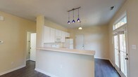 This two-story home at 3238 offers a well-organized layout designed for comfortable everyday living. The main level centers around an open-concept living and kitchen area, where dark hardwood-style flooring runs throughout, creating a cohesive and polished look. The kitchen is equipped with white cabinetry offering generous storage, light countertops, and a full suite of white appliances including a range, built-in microwave, and refrigerator. A peninsula-style breakfast bar separates the kitchen from the living area, with a trio of distinctive blue pendant lights above providing focused illumination. A separate entry door with a transom window welcomes natural light into the foyer. A dedicated laundry area is also found on the main level, along with access to the attached garage, which features a windowed overhead door and an electrical panel.

Upstairs, carpeted bedrooms provide a quieter retreat. At least one bedroom includes a walk-in closet with wire shelving, while another features a sliding double closet. The bathroom is fitted with a full tub-and-shower combination with clean white surround. Warm yellow-toned walls throughout the home contribute to a bright and inviting atmosphere.
